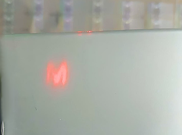 Small piece of hologram sticker with laser covert image showing M